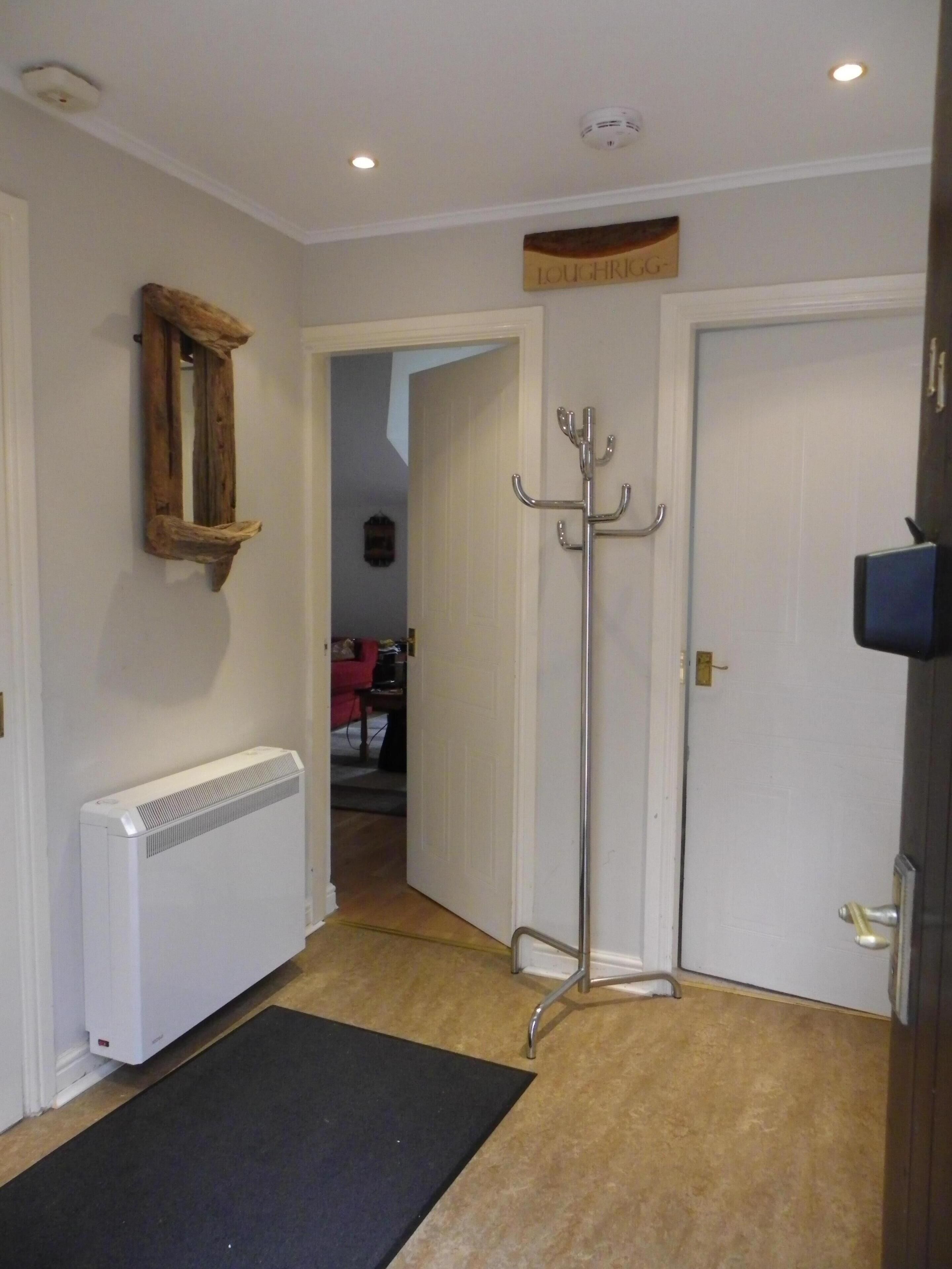 A hallway with a radiator, a coat rack, and a door leading to another room.