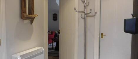 A hallway with a radiator, a coat rack, and a door leading to another room.