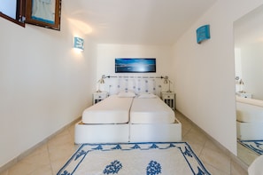 Une chambre à coucher avec un grand lit, une table de chevet, une commode, un téléviseur fixé au mur et un miroir.