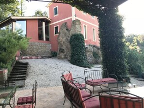 A patio area with outdoor seating, a stone staircase, and a building with a red facade and stone walls. - The red house on the roman arch with private pool all for you (Otricoli)