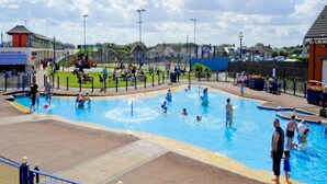 A swimming pool area with multiple pools, a covered seating area, and a playground.