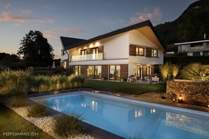 A modern two-story house with a swimming pool, surrounded by a landscaped garden and a mountain backdrop. - Montreux Holiday Home (Modern Villa) with view on the lake & the mountains (Blonay)