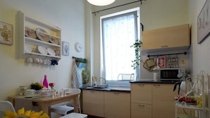 Une cuisine avec une table en bois, des chaises blanches, un évier et un four à micro-ondes.