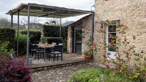 A stone building with a covered patio area featuring a table and chairs. - Torretta - Luxury rustico with pool and air conditioning EV wallbox (Camaiore)