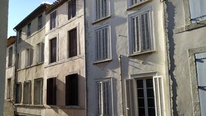 A multi-story building with several windows, some with shutters, and a visible storefront with a sign. - Unique Space in the Heart of La Bastide (Carcassonne)