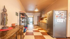 A narrow hallway with a checkered floor, a wooden table with a statue, a refrigerator with magnets, and a door leading to another room. - Unique Space in the Heart of La Bastide (Carcassonne)