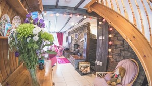 A cozy interior with a wooden archway, a fireplace, and a plush chair with a teddy bear.