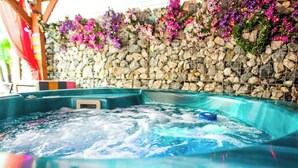 A hot tub with a stone wall and purple flowers in the background. - "266" 4 STAR!  HOT-TUB, LOG-FIRE, BQ, PLAYGROUND, BIKE LOCKUP, Nr Zip World  (Aberdare)
