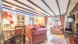 A cozy living room with a sofa, armchair, and a TV mounted on a stone wall. - "266" 4 STAR!  HOT-TUB, LOG-FIRE, BQ, PLAYGROUND, BIKE LOCKUP, Nr Zip World  (Aberdare)