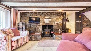 A cozy living room with a stone fireplace, striped sofas, and a television mounted on the wall. - "266" 4 STAR!  HOT-TUB, LOG-FIRE, BQ, PLAYGROUND, BIKE LOCKUP, Nr Zip World  (Aberdare)