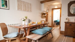 A wooden dining table with benches, a white radiator, and a wall-mounted radio.