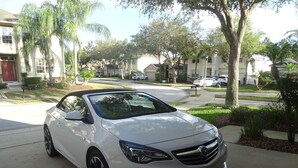 A white sedan parked on a residential street. -  Stylish Ever Popular House with Large Solar Heated Pool/Spa in Gated Community  (Davenport)