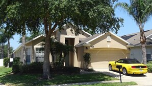 A residential house with a garage, a driveway, and a yellow car parked in front. -  Stylish Ever Popular House with Large Solar Heated Pool/Spa in Gated Community  (Davenport)