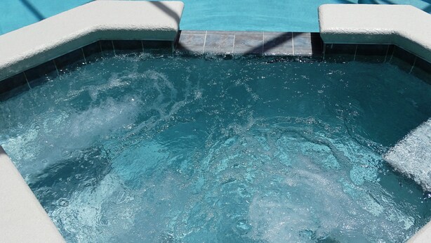 A hot tub with a tiled edge and a clear view of the water. -  Stylish Ever Popular House with Large Solar Heated Pool/Spa in Gated Community  (Davenport)