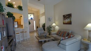 A modern living room with a white sofa, a coffee table, and a bookshelf. -  Stylish Ever Popular House with Large Solar Heated Pool/Spa in Gated Community  (Davenport)