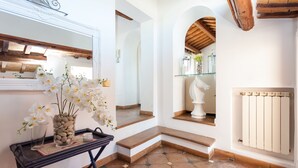 A clean, modern interior with a stone vase of white flowers, a glass shelf with decorative items, and a white radiator.
