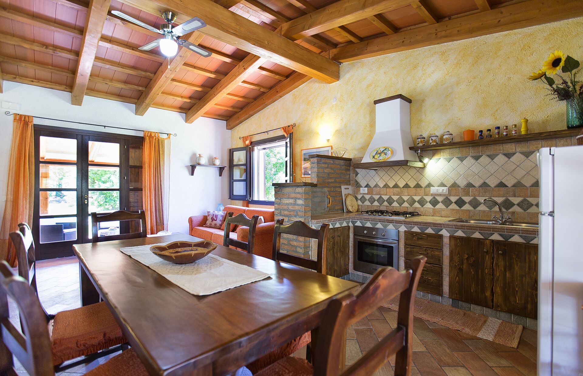 Una cocina rústica con techo de madera, una mesa de comedor con sillas, una estufa y un refrigerador.