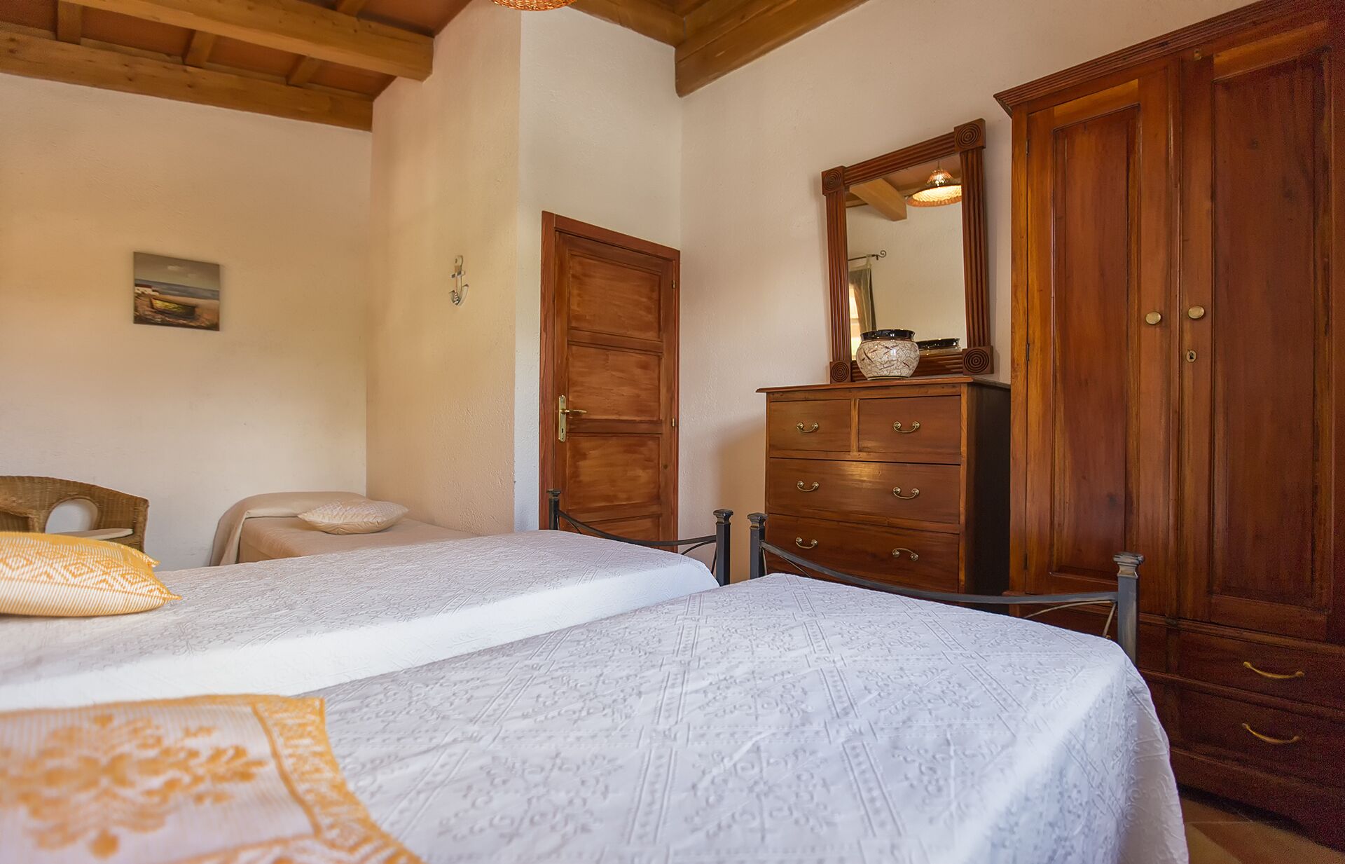 Une chambre avec deux lits, une armoire en bois et une commode.