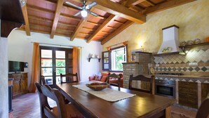 A rustic kitchen with a wooden ceiling, a stone fireplace, and a dining area with a table and chairs. - ClickSardegna Villa Porticciolo near the beach for 6 people, with A/C and WiFi (Alghero)