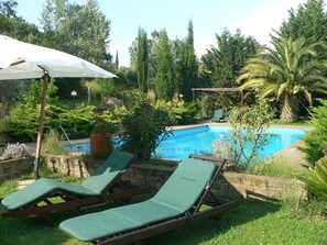Un espace piscine comprenant deux chaises longues et un auvent.