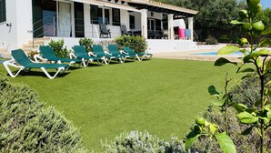 Una villa moderna con piscina, césped verde y zona de estar al aire libre.
