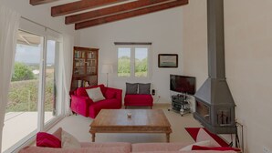 Una sala de estar con un sofá rojo, una mesa de centro de madera, una chimenea y una estantería.