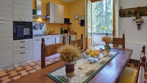 A kitchen with a dining table, chairs, and a window with a view of trees. -  "Villa Torre in Chianti"  Vrbo Vacation Rental of the Year 2026- 8 bedrooms A/C (San Casciano in Val di Pesa)