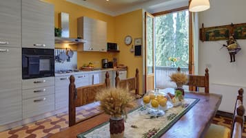 A kitchen with a dining table, chairs, and a window with a view of trees.