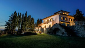 A large, two-story house with a stone wall entrance, a balcony, and a well-lit garden area. -  "Villa Torre in Chianti"  Vrbo Vacation Rental of the Year 2026- 8 bedrooms A/C (San Casciano in Val di Pesa)