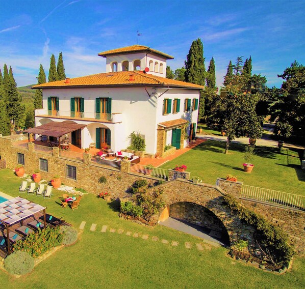 A two-story house with a balcony, a stone bridge, and a well-maintained lawn. -  "Villa Torre in Chianti"  Vrbo Vacation Rental of the Year 2026- 8 bedrooms A/C (San Casciano in Val di Pesa)