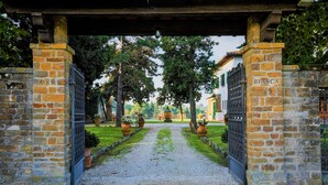 A stone gate with "TORRE" and "BIANCA 69" signs, leading to a gravel path flanked by potted plants and trees. -  "Villa Torre in Chianti"  Vrbo Vacation Rental of the Year 2026- 8 bedrooms A/C (San Casciano in Val di Pesa)