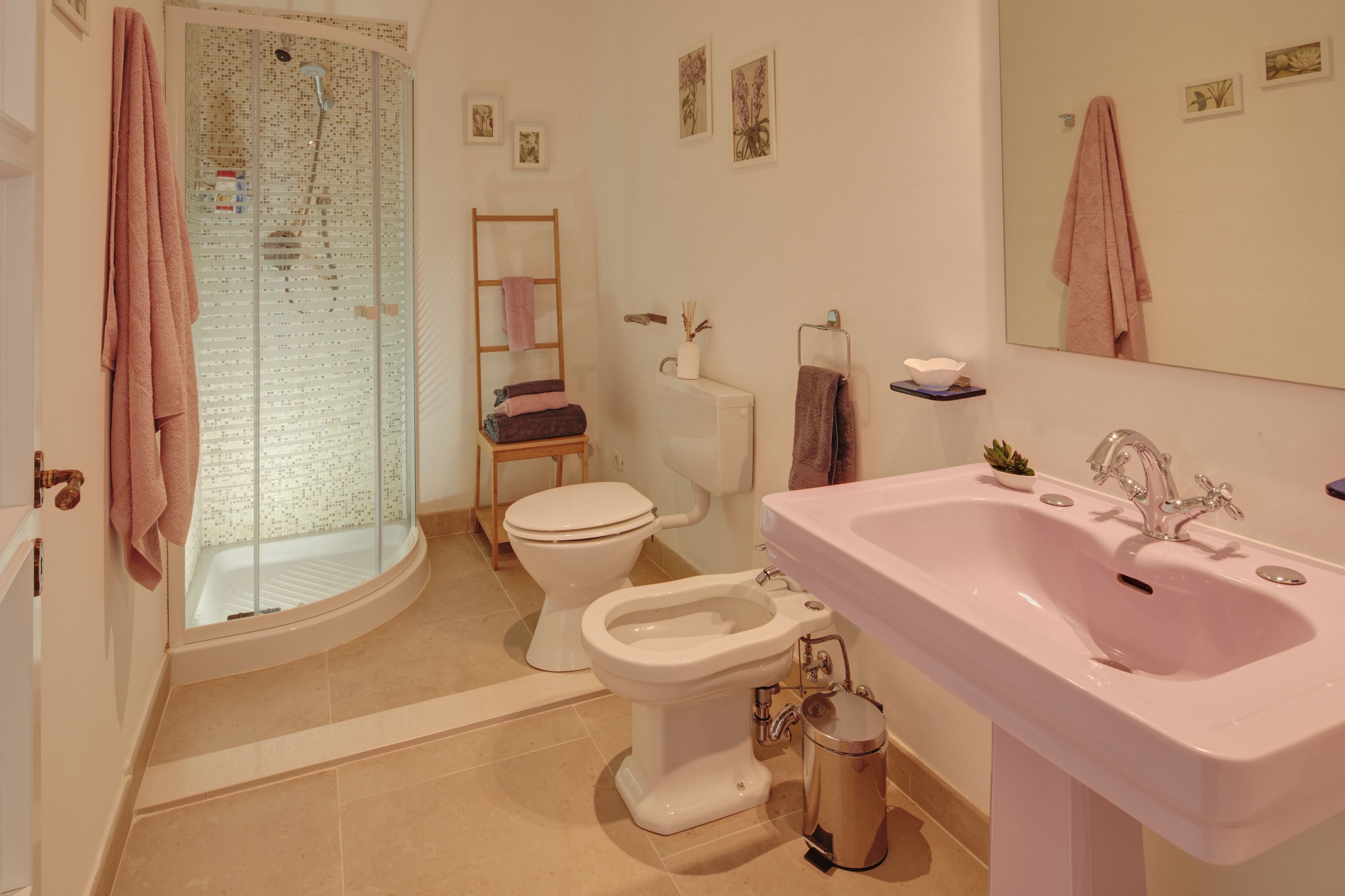 A bathroom with a glass shower enclosure, a toilet, a bidet, and a sink.