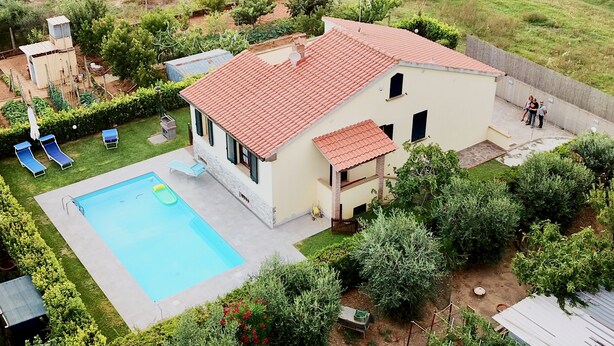 Une maison à deux étages avec une piscine, un patio couvert et un jardin.