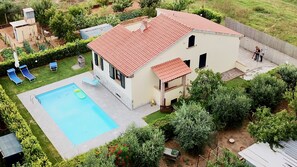 Ein zweistöckiges Haus mit Swimmingpool, überdachter Terrasse und Garten.