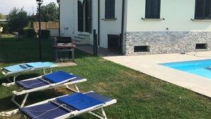 Un espace aménagé au bord de la piscine, avec des chaises longues et un patio couvert.