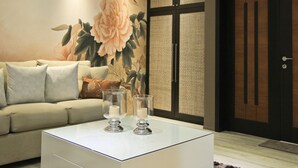 A modern living room with a beige sofa, two glass candle holders, and a large floral mural on the wall. - Boracay Suites (Boracay Island)