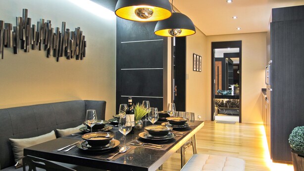 A modern dining area with a long table set for a meal, featuring black and white decor and a unique wall art installation. - Boracay Suites (Boracay Island)