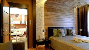 A hotel room with a wooden ceiling, a bed with a beige bedspread, a nightstand with a lamp, and a chair. - Boracay Suites (Boracay Island)