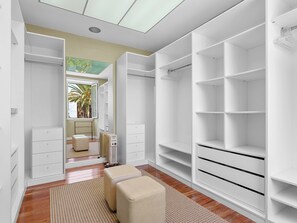 Un dressing accessible sans porte, avec un radiateur et une vue sur une pièce où se trouvent un lit et une fenêtre.