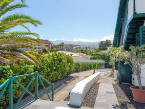 Un chemin menant à un bâtiment d’où l’on peut admirer un quartier résidentiel et des montagnes au loin.