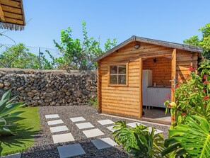 Une cabane en bois avec un mur en pierre, un chemin pavé et une végétation luxuriante.