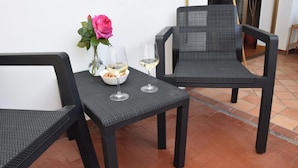 Une table avec deux chaises, un vase avec une fleur et deux verres à vin.