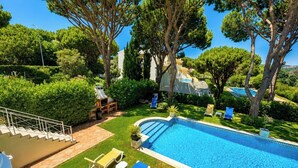 Une piscine avec des chaises longues, un escalier et une vue sur un bâtiment doté d’une autre piscine.