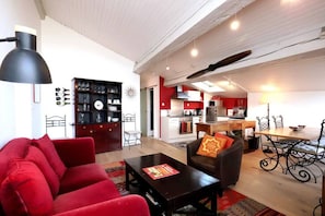 A living room with a red sofa, a black coffee table, and a dining area with a wooden table and chairs.