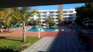 A pool area with blue lounge chairs and a building in the background. - Exquisite one-bedroom apartment in Lagos Marina  (Lagos)