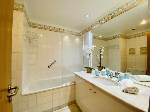 A bathroom with a bathtub, a sink, a mirror, and a shower.