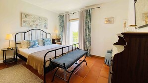 A bedroom with a bed, bedside tables, a bench, a dresser, and a window with curtains. - Exquisite one-bedroom apartment in Lagos Marina  (Lagos)