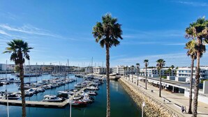 A marina with numerous boats docked, surrounded by palm trees and a stone wall. - Exquisite one-bedroom apartment in Lagos Marina  (Lagos)