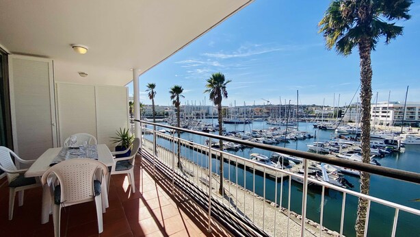 A balcony with a view of a marina, white chairs, and a table. - Exquisite one-bedroom apartment in Lagos Marina  (Lagos)