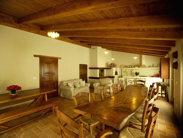 Un vaste espace dédié à la salle à manger, avec une longue table en bois et des chaises, un banc en bois et un canapé.